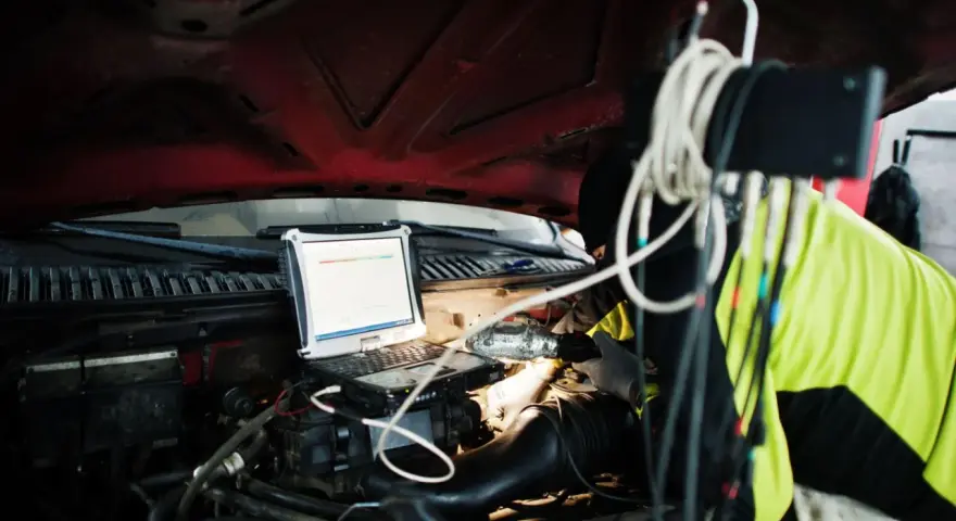 Mechanik diagnozuje problem DTC P0606 Renault za pomocą laptopa pod maską.