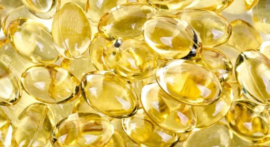 En hög med genomskinliga, gulaktiga kapslar som liknar solens strålar. Dessa kan vara vitaminer som ger energi.