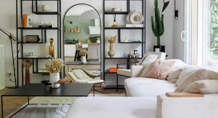 Soggiorno con divano bianco, librerie nere, specchio ad arco e cactus. Un'oasi di pace in stile casa minimal.