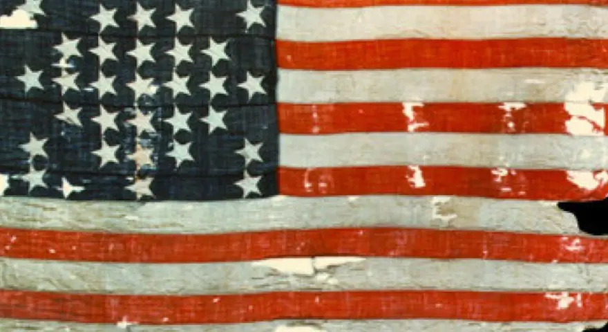 Pierwsza flaga USA, zniszczona i wyblakła, z 13 gwiazdami i pasami, świadectwo historii.