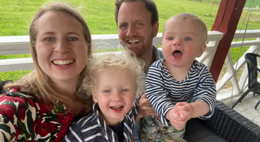 Familj med barn på en altan med grönskande landskap i bakgrunden. En härlig stund med norge med barn.