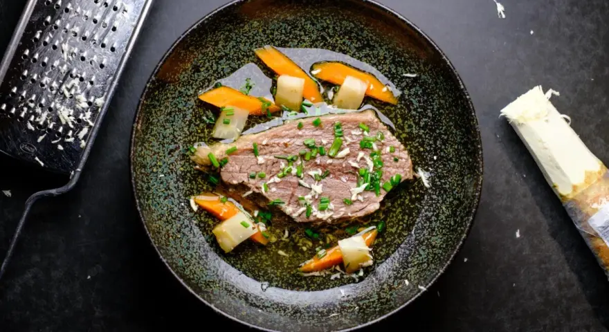 Zarter Tafelspitz braten im Topf, serviert mit Karotten und Lauch. Frisch geriebener Meerrettich daneben.