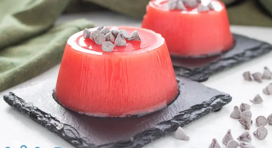 Delizioso gelo di melone, un dolce fresco e colorato, guarnito con gocce di cioccolato.
