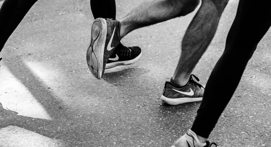 Gambe di corridori in azione, con particolare attenzione al consumo delle scarpe sportive Nike.