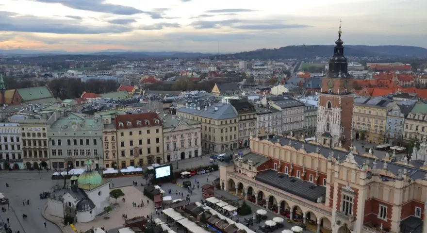 Widok na Rynek Główny w Krakowie z dominującą wieżą mariacką. Widać Sukiennice, kościół św. Wojciecha i stragany jarmarku.