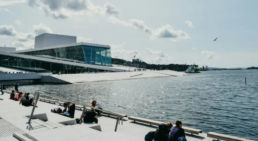 Oslo fiordy jak dojechać: nowoczesna Opera Narodowa i ludzie odpoczywający nad wodą.