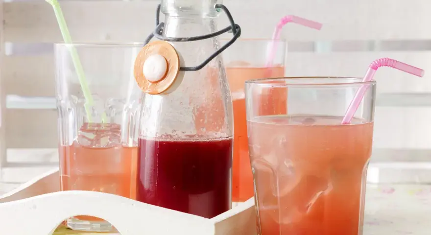 Erfrischender Rhabarbersirup im Glas mit Eis und Strohhalm. Ein tolles Rezept für den Sommer!