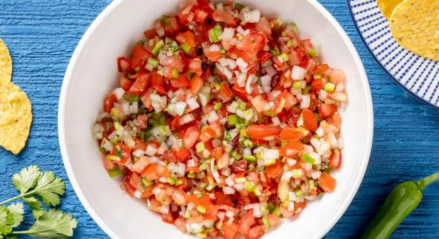 Pico de gallo ricetta: pomodori, cipolla, peperoncino e coriandolo freschi, pronti per essere gustati con nachos.