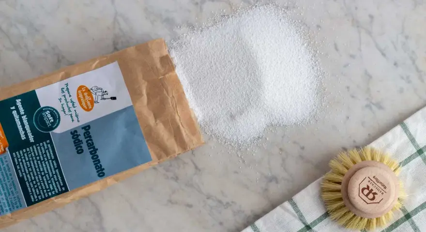 Percarbonato sódico, ideal para ropa color, se derrama de su bolsa junto a un cepillo.