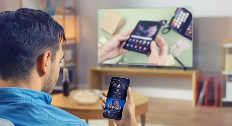 Mann verbindet sein Handy mit dem Fernseher, um ein Video anzusehen. Auf dem Handy ist ein YouTube-Video zu sehen.