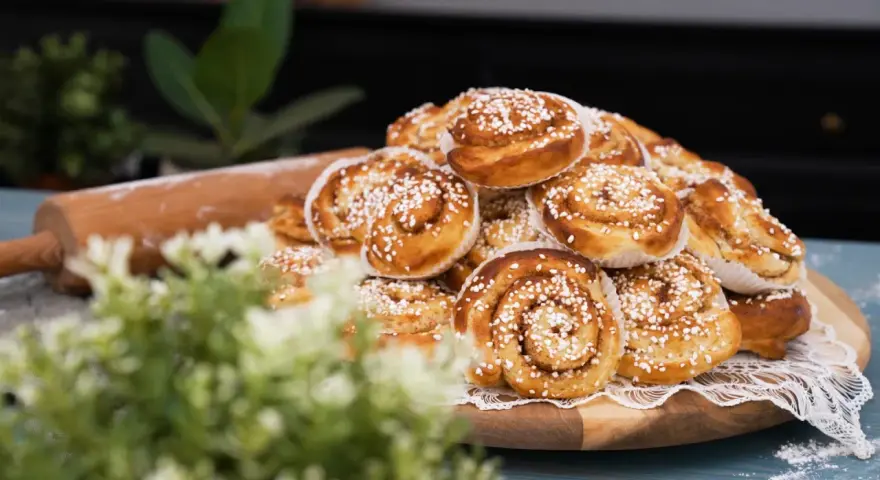 En hög med gyllene kanelbullar, redo att bakas enligt ett enkelt kanelbullar recept. En kavel ligger bredvid.