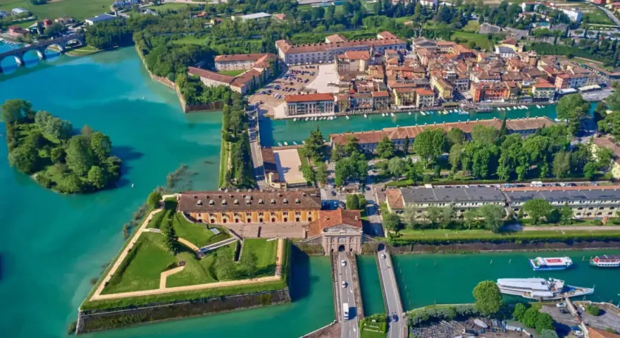 Peschiera del Garda centro storico: fortezza a stella circondata da acque turchesi, con edifici storici e un ponte.