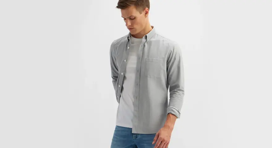 Mężczyzna w szarej koszuli i białej koszulce, prezentujący styl smart casual męski.