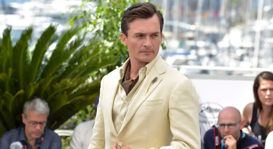 Hombre con un impecable corte de pelo old money, viste un traje de lino color crema y un pañuelo de seda.