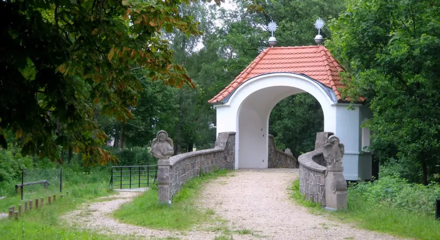 Kamienna furtka z aniołami prowadzi do Kalwarii Wielewskiej. Kręta ścieżka wśród zieleni zaprasza do kontemplacji.