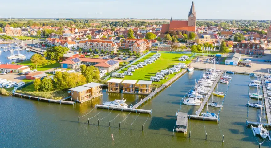 Blick auf Barth an der Ostsee mit Yachthafen, Wohnmobilstellplätzen und modernen Ferienhäusern am Wasser.