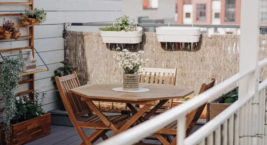 Holztisch mit Stühlen und Gänseblümchen, Wandregal mit Pflanzen, schöne Balkon Ideen für Ihr Zuhause.