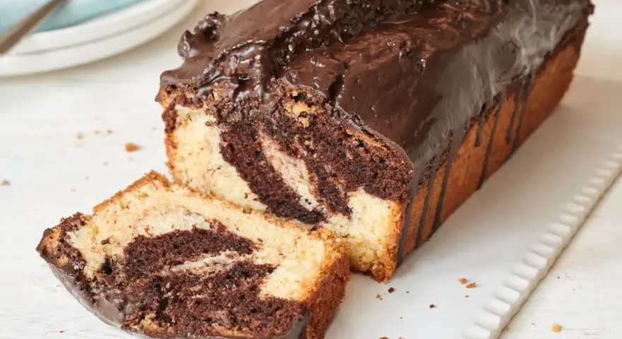 Saftiger Marmorkuchen, frisch aus dem Airfryer, mit Schokoladenglasur und einer angeschnittenen Scheibe.