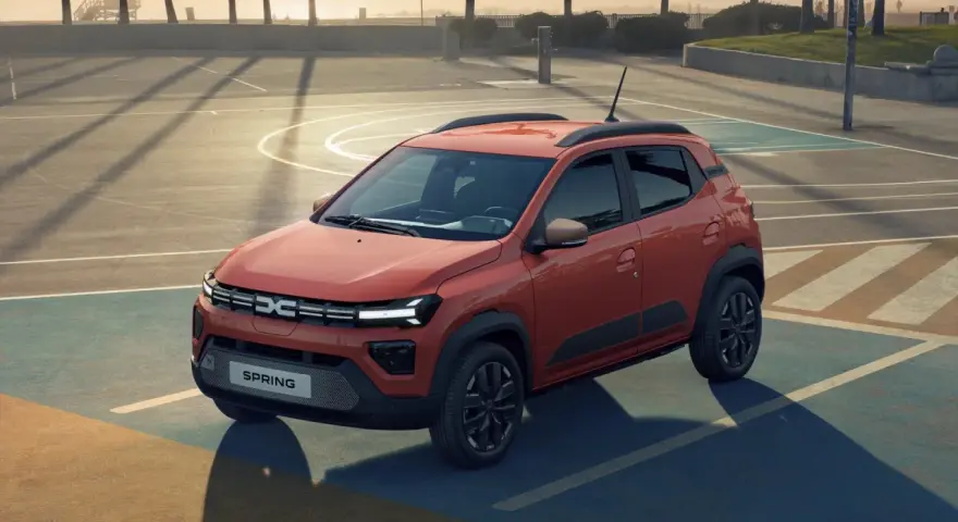 Pomarańczowy Dacia Spring na boisku. Sprawdź atrakcyjną dacia spring cena i odkryj jego możliwości.