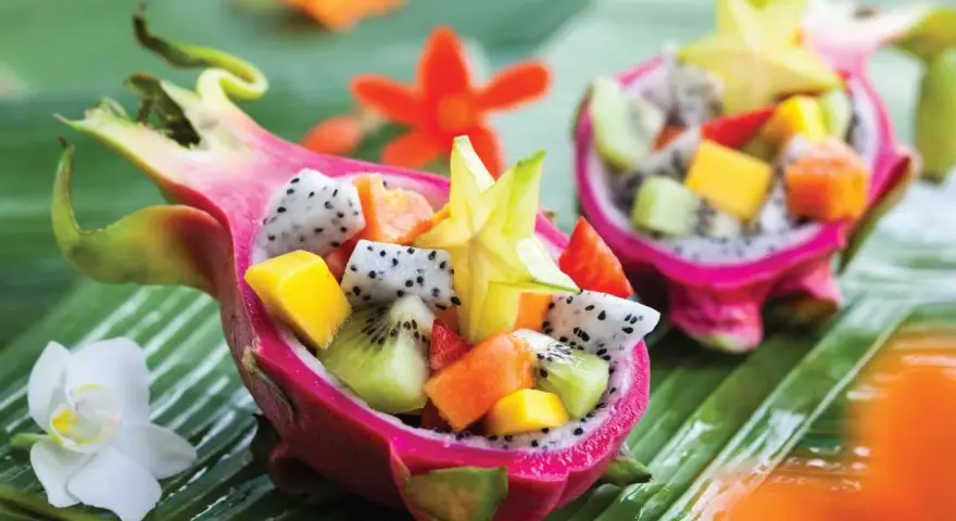 Smoczy owoc w formie miseczki wypełnionej egzotycznymi owocami: kiwi, mango, papają i karambolą.
