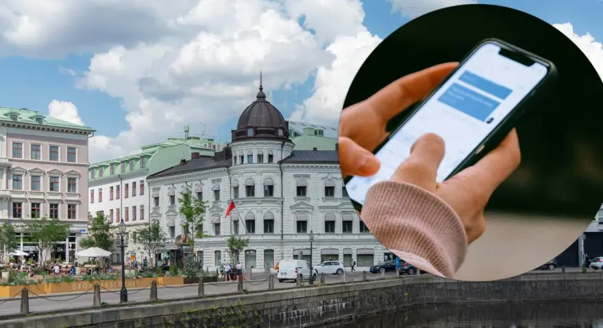 Dłoń trzymająca smartfon z widocznym oknem czatu na tle miejskiego krajobrazu z budynkami i rzeką.