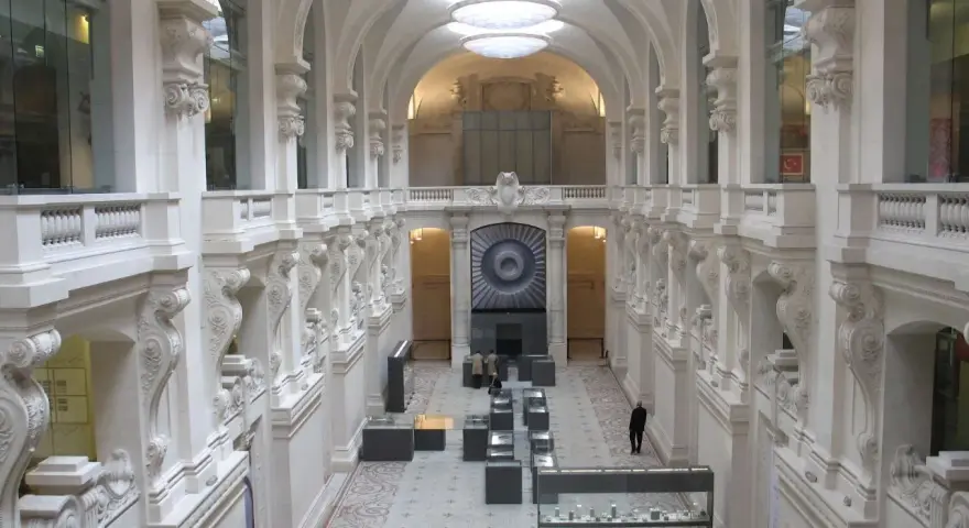 Interior del museo de artes decorativas, con arcos, balcones y vitrinas exhibiendo objetos.
