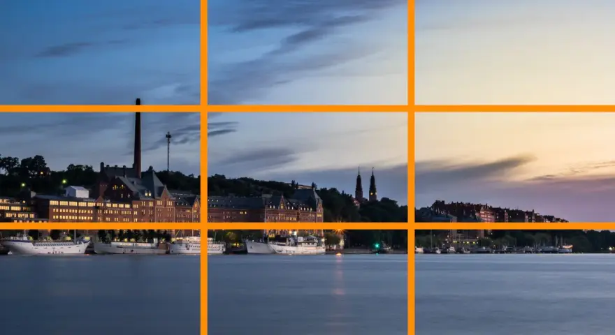Un paysage urbain au crépuscule, avec des bâtiments historiques et des bateaux le long de l'eau. Un excellent exemple pour un tuto photographie sur la règle des tiers.
