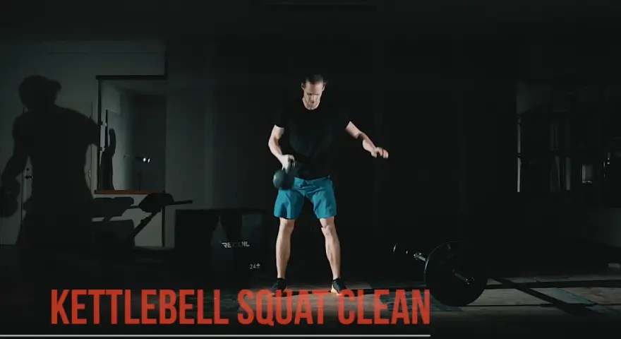 Man utför en kettlebell clean i ett mörkt gym.