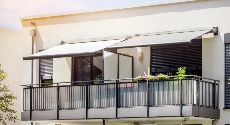 Nowoczesny balkon z balustradą i markizami. Szklana ścianka to pomysł, jak odgrodzić balkon, zapewniając prywatność i styl.