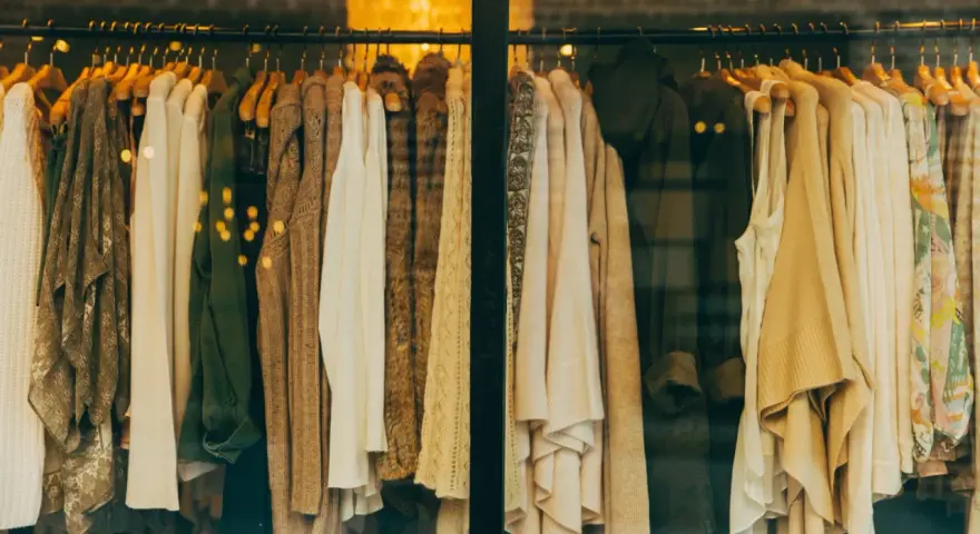 Vetrine di un negozio di abbigliamento con capi in tonalità neutre. Il **store manager** ha scelto un'esposizione elegante.