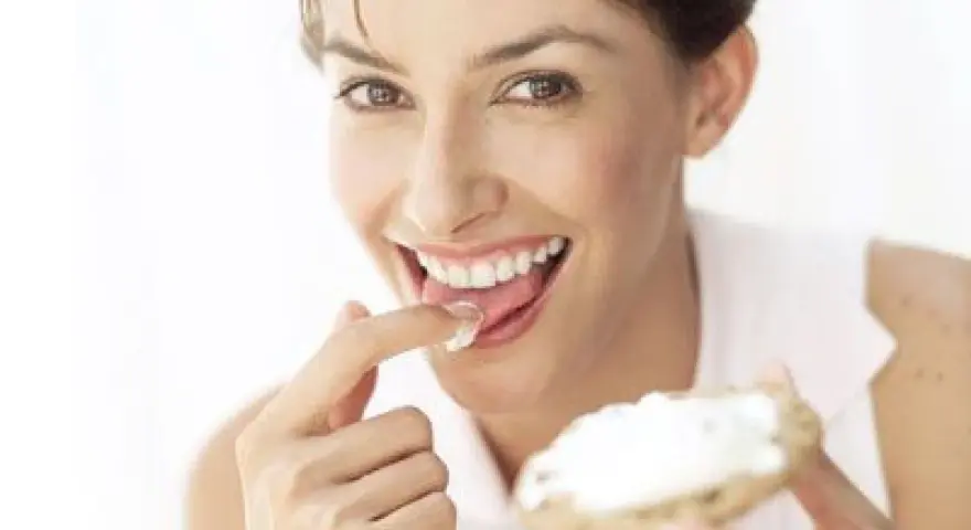 Une femme savoure une bouchée de pain avec de la saint agur crème enceinte, un sourire aux lèvres.