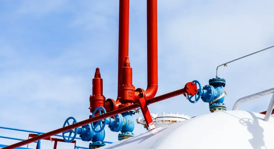 Zawory i rury przy białym zbiorniku na gaz. Zastanawiasz się, na ile wystarcza zbiornik na gaz 2700?