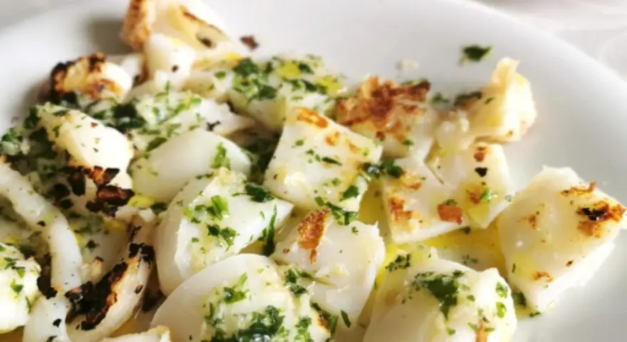 Sabrosa sepia a la plancha, cortada en trozos y aderezada con perejil fresco y aceite de oliva.