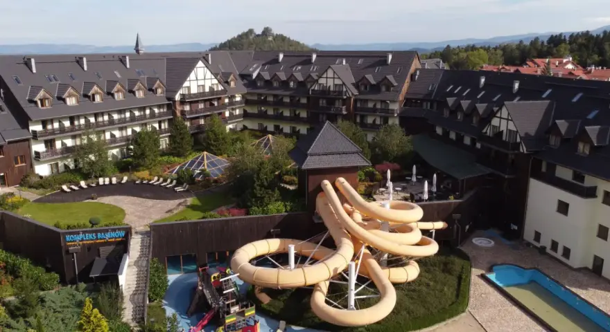 Karpacz hotel z aquaparkiem oferuje zjeżdżalnie i baseny. Widać też góry w tle.