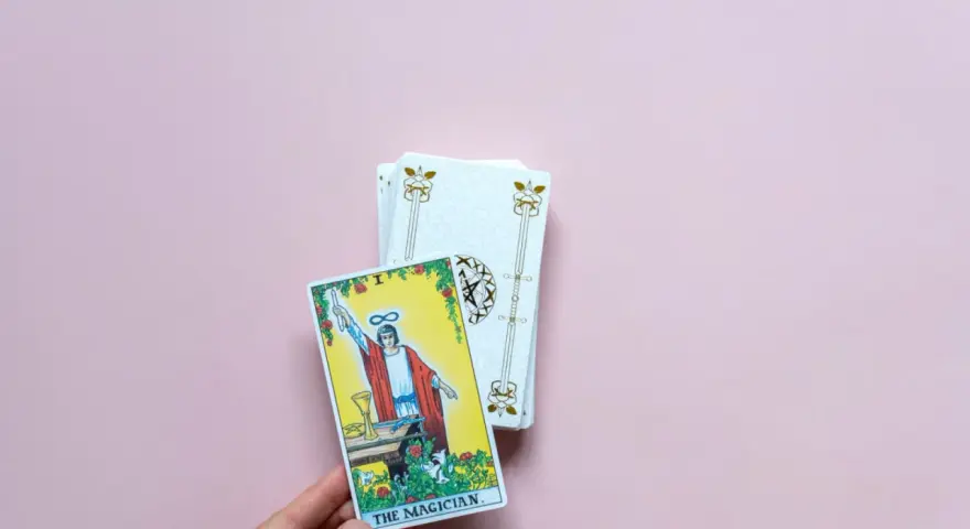Mano sostiene la carta "El Mago" de un tarot del amor presente pasado y futuro.