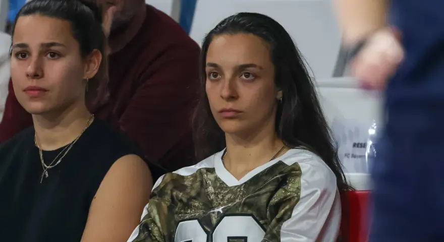 Natalia Padilla Bidas, zamyślona, siedzi na trybunach w koszulce z motywem kamuflażu.
