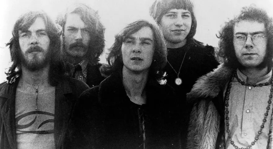 Cinq membres de King Crimson posent ensemble, arborant des coiffures et des vêtements typiques des années 70.