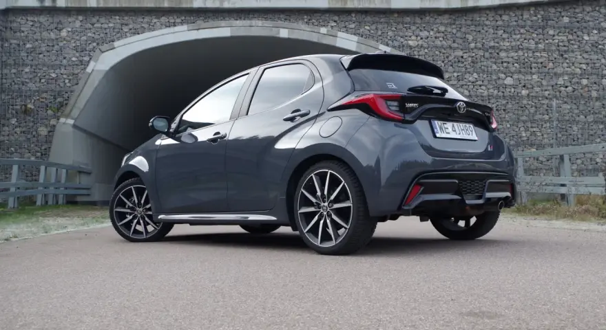 Szary Toyota Yaris Hybrid stoi przed tunelem. Dowiedz się, ile pali Toyota Yaris Hybrid, analizując jego osiągi.