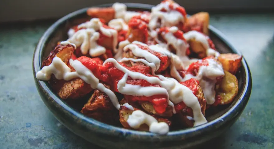 En skål med krispiga patatas bravas, toppade med en kryddig tomatsås och krämig aioli.