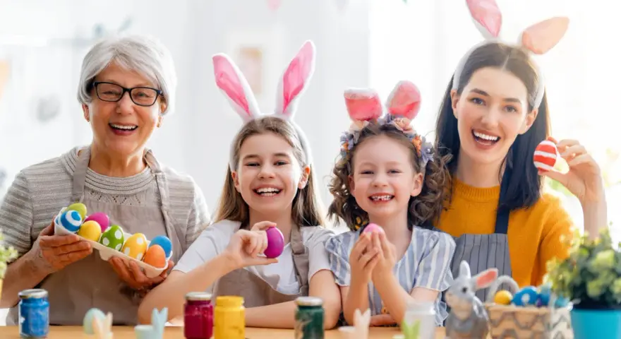 Familie feiert die Osterferien BW 2026 mit bunten Eiern und Hasenohren.