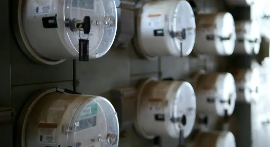 Rząd liczników energii elektrycznej, każdy z plombą. Jeden z nich, jako sprzedawca rezerwowy, jest widoczny z bliska.