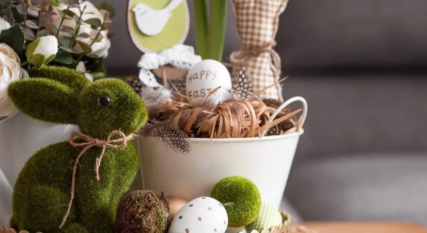 Zielony, mchowy zajączek i pisanki tworzą najpiękniejsze dekoracje wielkanocne. W koszyku jajko z napisem "Happy Easter".
