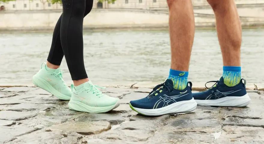 Två par löparskor, mintgröna Asics Gel Luminus 2 dam och mörkblå herrskor, står på stenar vid en flod.