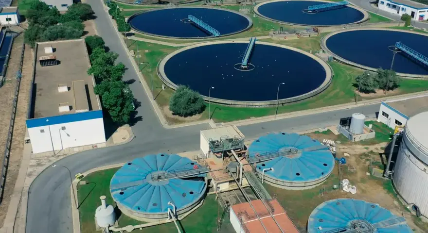 Vista aérea de una planta de depuración de aguas con grandes tanques circulares y estructuras industriales.