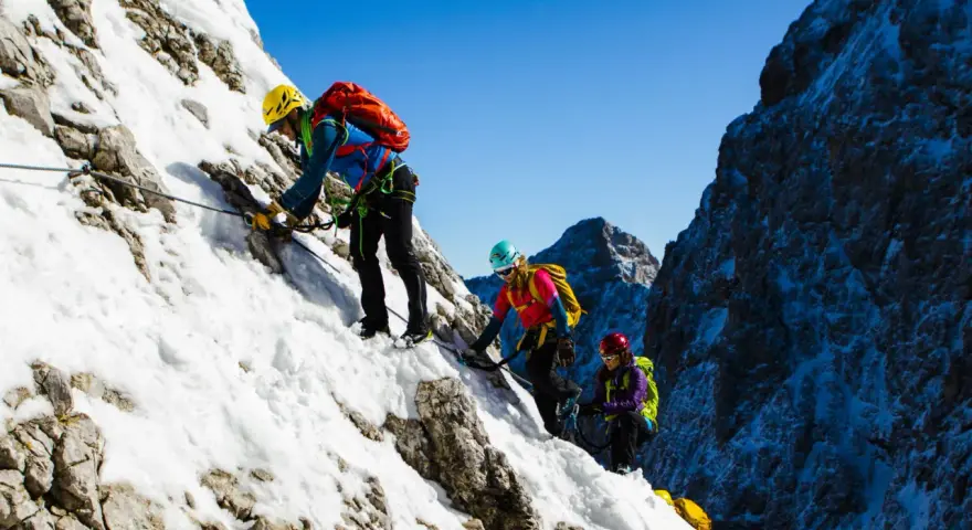 Drei Bergsteiger meistern den Klettersteig Zugspitze im Schnee.
