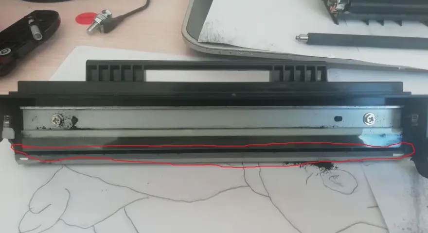 Rozłożony sp112 toner z widocznym wałkiem i resztkami proszku. Czerwona linia zaznacza uszkodzony element.