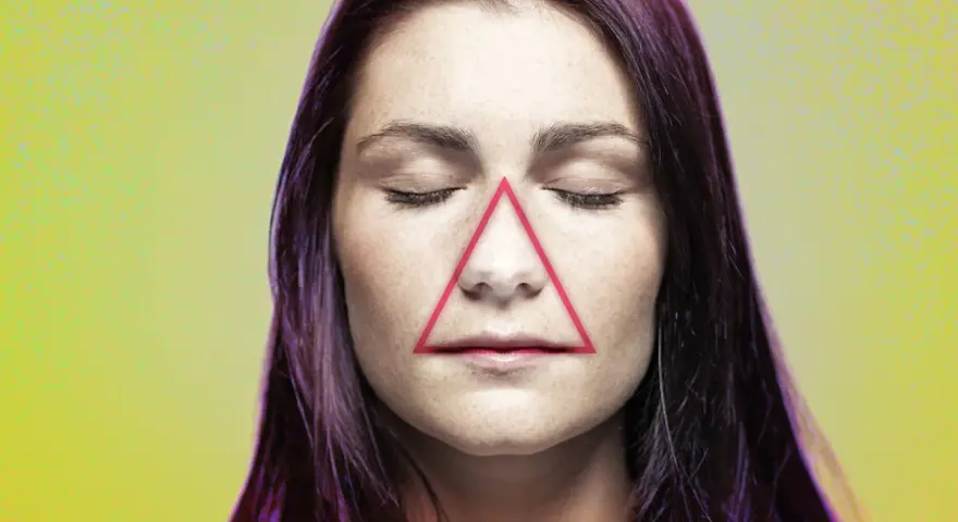 Frauenkopf mit geschlossenen Augen, auf dessen Nase und Mund ein rotes Dreieck liegt. Ein Pickel im Todesdreieck im Gesicht kann gefährlich sein.