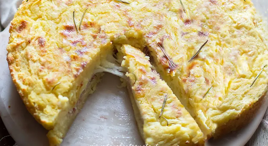 Una fetta di torta di patate filante, dorata e profumata al rosmarino, pronta per essere gustata.