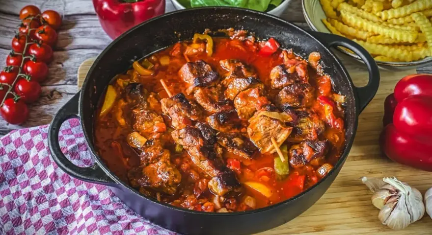 Herzhaftes Schaschlik-Rezept in Gusseisenpfanne mit Paprika, Zwiebeln und Tomaten. Dazu Pommes und frische Zutaten.