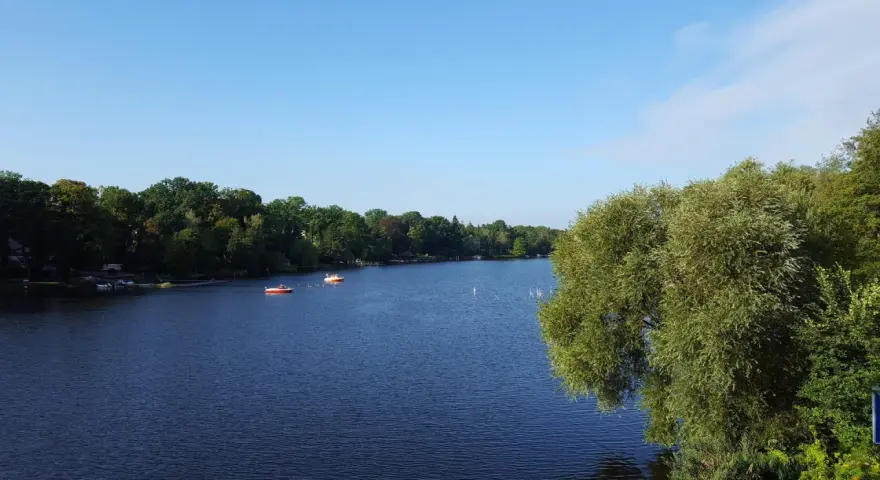 Ein ruhiger See mit Booten, umgeben von grünen Bäumen. Ein perfekter Ort für einen entspannten Tag, ein echter Geheimtipp in Berlin.